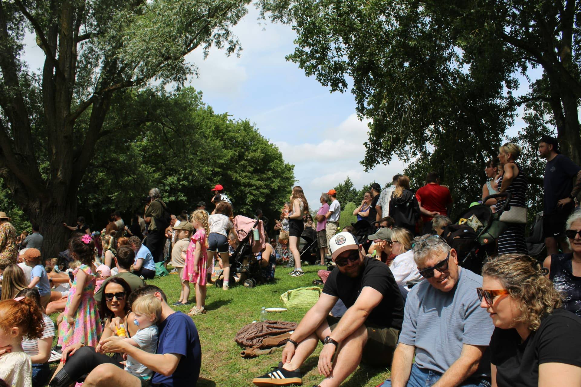 Crowd of families at an outdoor Orange County event under the trees